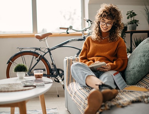 IMAGE: Young woman sitting on couch reading.