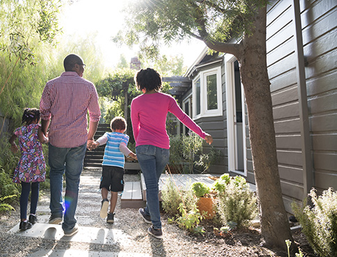 IMAGE: Family of four walking along side of house.