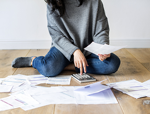 IMAGE: woman sitting on floor with calculator and papers