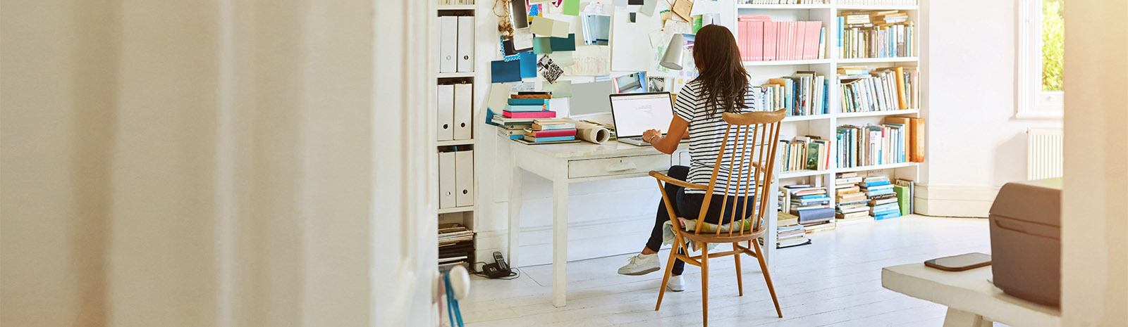 IMAGE: Woman on computer facing away sitting at desk