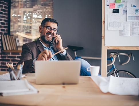 IMAGE: Mature businessman on phone at his laptop