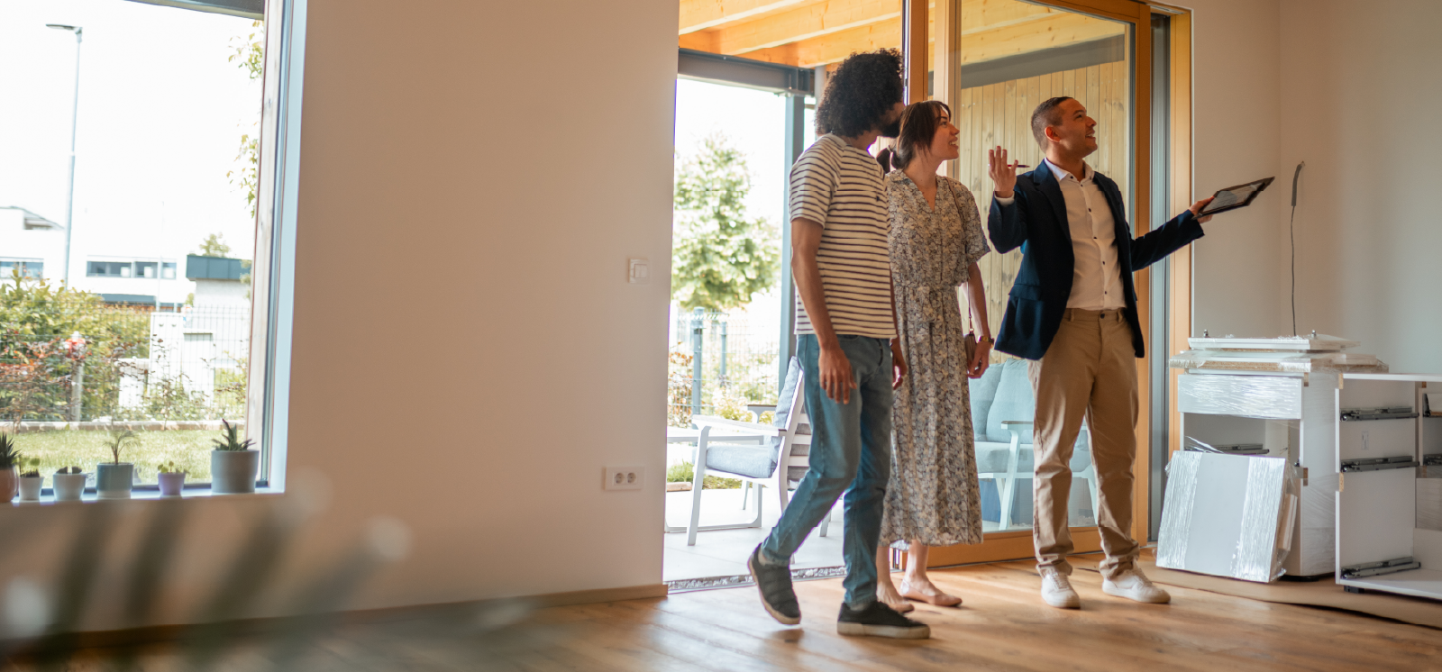 IMAGE: Couple talking with realtor inside a house.