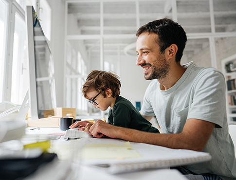 IMAGE: Man at computer with young son on his lap